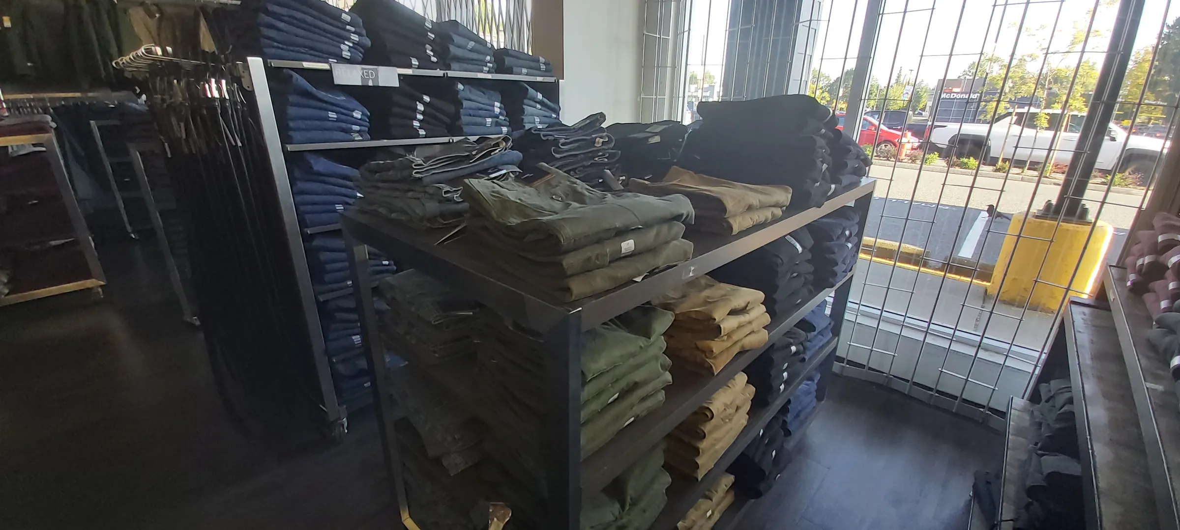 Jeans on racks and folded on a table beside the store's front windows