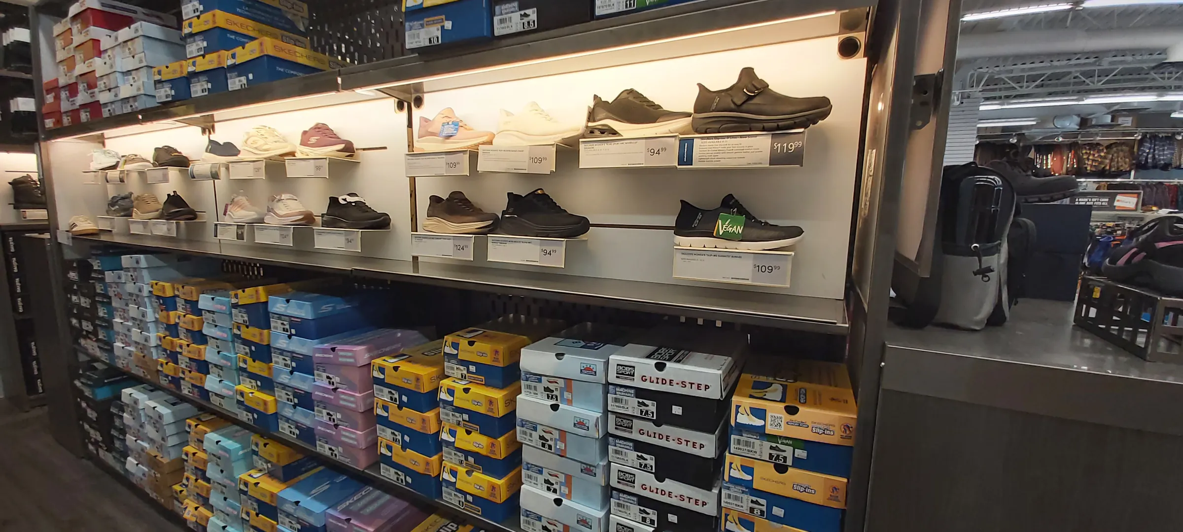 A lit shoe wall with casual and slip-on styles above and boxed sizes below