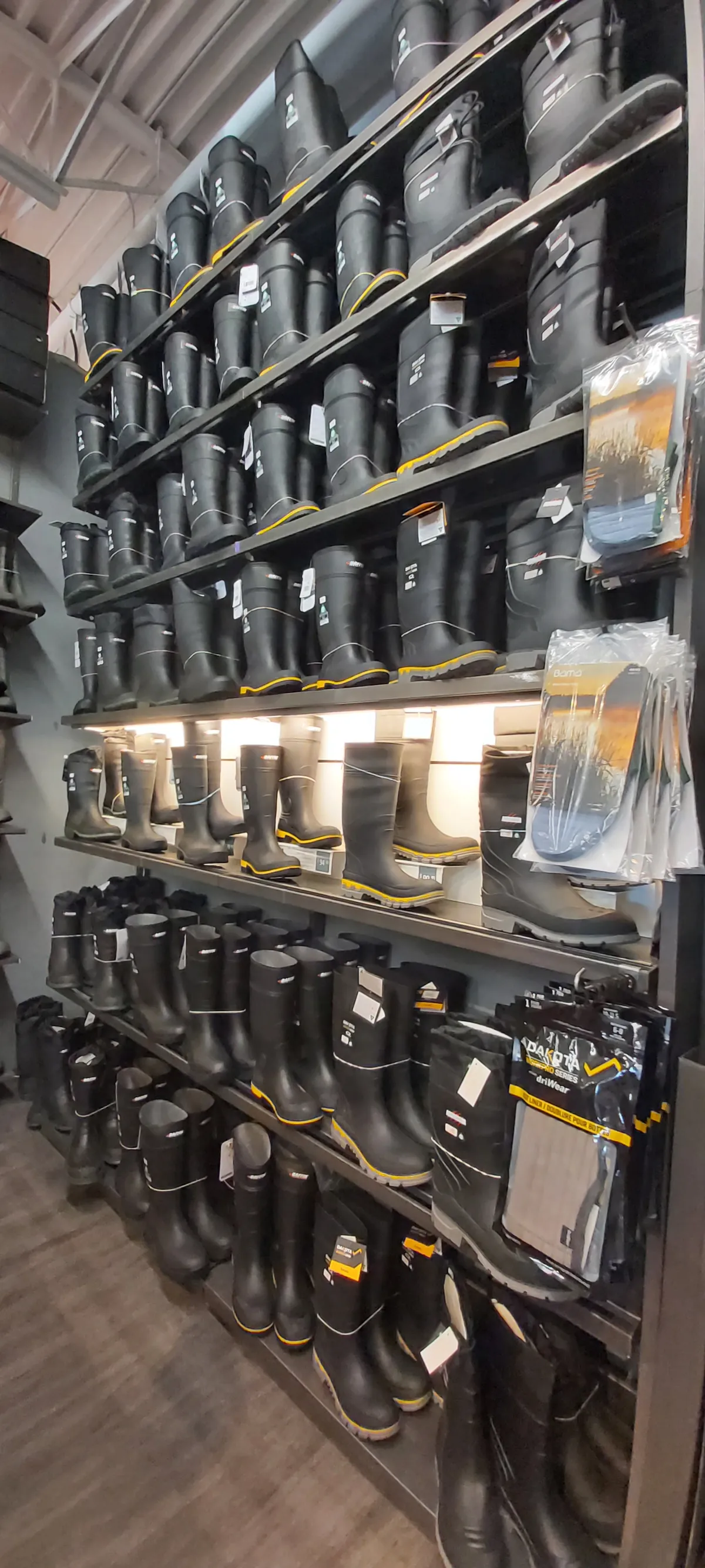 Work and safety boots on a full-height display wall, with rubber boots on the lower shelves